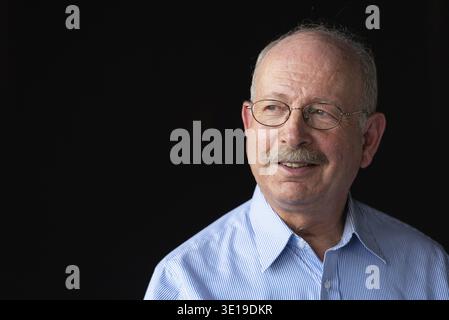 Grauhaariger älterer Mann mit lächelndem Schnurrbart und Denken vor schwarzem Hintergrund Stockfoto