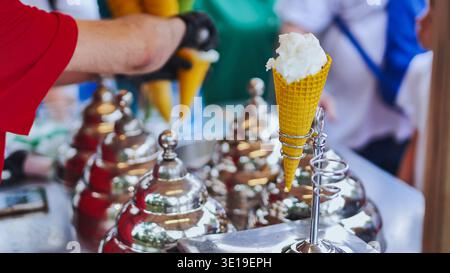 Verkäufer serviert erfrischende Eiskegel in einem Waffelkaffee und süßen Dessert-Erlebnis Stockfoto