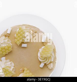 Blick von oben auf einen Zitronenkäsekuchen mit weißen cremefarbenen Belägen und Kokosflocken, isoliert auf weiß Stockfoto