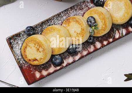 Elegante Hüttenkäsepfannkuchen auf Teller mit Blick von oben Stockfoto