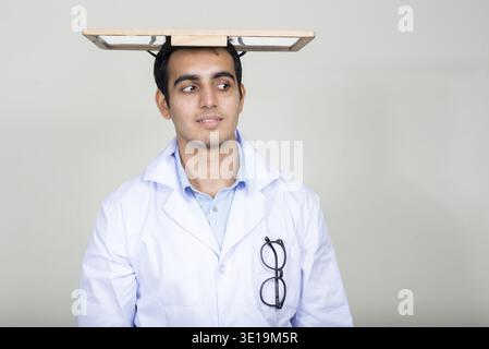 Studio shot der jungen schönen Indischen mann Arzt vor weißem Hintergrund Stockfoto