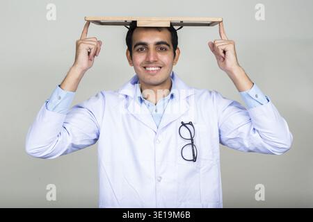 Studio shot der jungen schönen Indischen mann Arzt vor weißem Hintergrund Stockfoto
