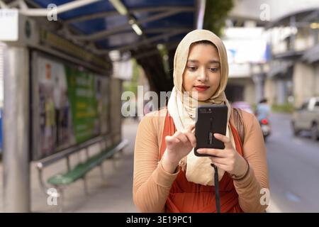Porträt einer jungen, schönen indischen Musliminnen mit Hijab an der Bushaltestelle in der Stadt Stockfoto