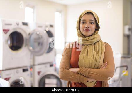 Porträt einer jungen, schönen indischen Musliminnen mit Hijab im Waschsalon drinnen Stockfoto