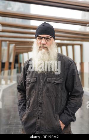 Porträt eines reiferen, gutaussehenden bärtigen Hipster-Mannes am Fußgängersteg in der Stadt Stockfoto