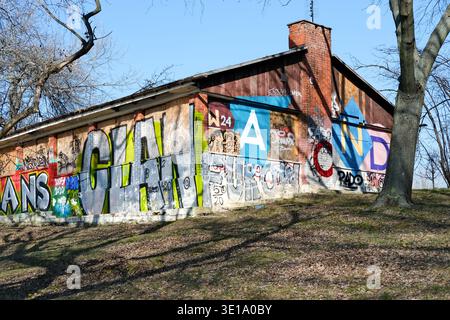 Graffiti-überdachtes Gebäude mit Holzfenstern und gemauertem Kamin in einem Stadtgebiet Stockfoto