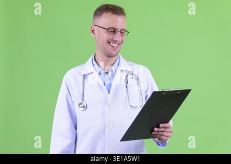 Studio-Aufnahme eines gutaussehenden Doktors, der eine Brille vor grünem Hintergrund trägt Stockfoto
