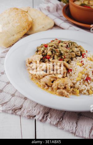 Huhn mit Reis, Auberginen-Salat und Brot auf weißem rustikalem Tisch mit einem Tontopf auf dem Hintergrund, das eine gesunde, hausgemachte Mahlzeit darstellt Stockfoto