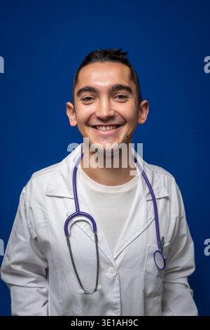 Junger Arzt lächelt mit weißem Mantel und Stethoskop Stockfoto