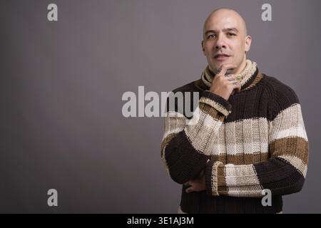 Studio shot der stattliche Mann mit Glatze rollkragen pullover gegen grauer Hintergrund Stockfoto