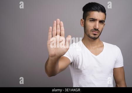 Studio shot der jungen schönen persischen Mann gegen grauer Hintergrund Stockfoto