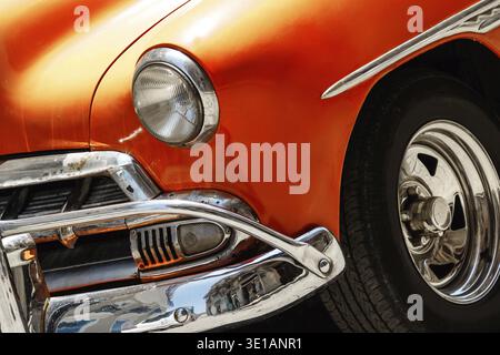 Nahaufnahme eines glänzenden Oldtimers in Orange, der auf der Straße geparkt ist Stockfoto