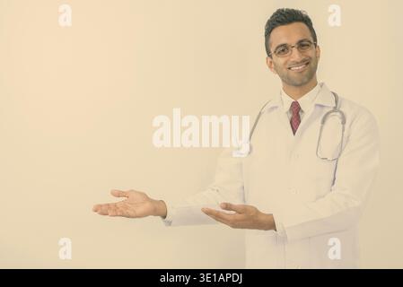 Studio shot der jungen schönen Indischen mann Arzt vor weißem Hintergrund Stockfoto