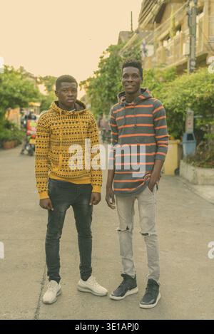 Voller Körper geschossen von zwei jungen schwarzen afrikanischen Freunde glücklich lächelnd beim Stehen im Freien Stockfoto