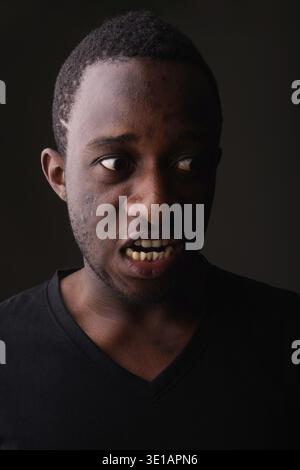 Studioaufnahme eines wütenden jungen schwarzen afrikanischen Mannes, der in schreit Dunkles Zimmer Stockfoto