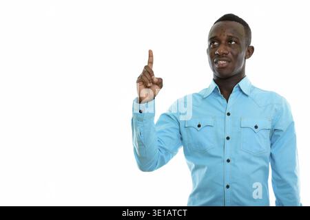 Studio shot der jungen schwarzen afrikanischen Mann glücklich lächelnd und denken, während Finger nach oben zeigen Stockfoto