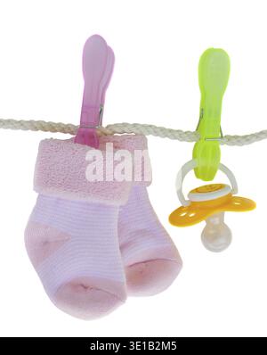 Rosafarbene Babysocken mit Schnuller, die isoliert am Seil hängen Stockfoto