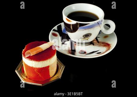 Obstgebäck aus Passionsfrucht und Himbeeren auf schwarzem Hintergrund mit einer Tasse Kaffee Stockfoto