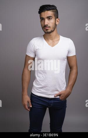 Studio shot der jungen schönen persischen Mann gegen grauer Hintergrund Stockfoto