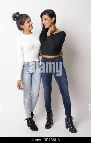 Studio-Aufnahme von zwei jungen schönen persischen Frauen zusammen als Schwestern vor weißem Hintergrund Stockfoto