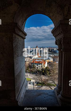 Blick auf das ungarische Parlamentsgebäude und die Donau durch den kunstvollen Steinbogen der Fischerbastei, Budapest, Ungarn Stockfoto