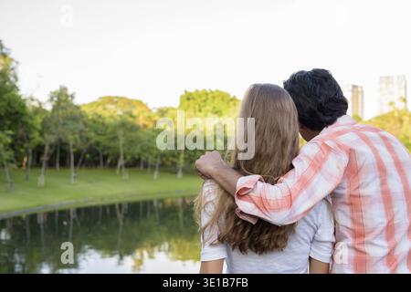 Rückansicht des multi-ethnische Paar in Liebe, während sie in einer ruhigen, grünen Park Stockfoto