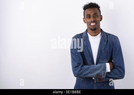 Studioaufnahme eines jungen bärtigen Afrikaners, der Denimjacke vor weißem Hintergrund trägt Stockfoto