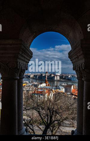 Blick auf das ungarische Parlamentsgebäude und die Donau durch den kunstvollen Steinbogen der Fischerbastei, Budapest, Ungarn Stockfoto