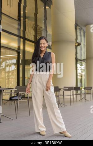 Ganzkörperportrait der schönen asiatischen Frau im Freien im Café-Restaurant vertikale Aufnahme Stockfoto