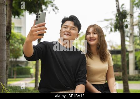 Junge glückliche asiatische Paare draußen im Park Stockfoto