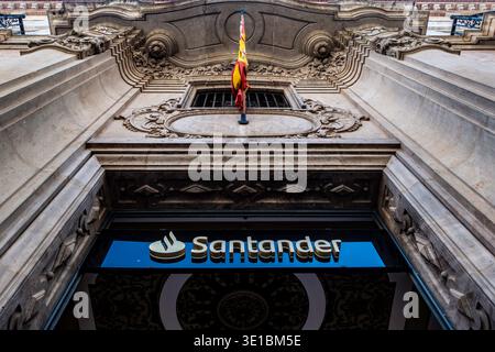 Flacher Blick auf das Santander-Uferschild und eine spanische Flagge an einer verzierten Steinfassade in Murcia, Spanien. Stockfoto