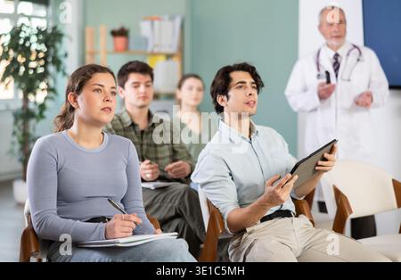 Die Studenten hören Vorlesungen im Klassenzimmer, mit einem Medizinprofessor im Hintergrund Stockfoto