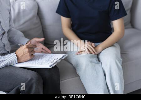 Traurige Frau sitzt auf Sofa Patient diskutiert psychische Probleme mit Psychologen. Depressive asiatische Frau psychische Gesundheit Behandlung Stockfoto