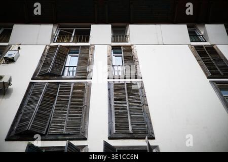 Eine professionelle Tiefwinkelaufnahme eines weißen Gebäudes. Die Fassade wird durch ein sich wiederholendes Muster von Fenstern mit dunklem, verwittertem Holz definiert Stockfoto