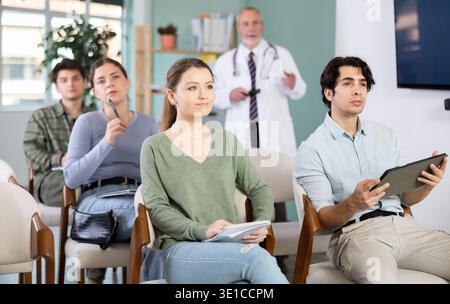 Die Studenten hören Vorlesungen im Klassenzimmer, mit einem Medizinprofessor im Hintergrund Stockfoto