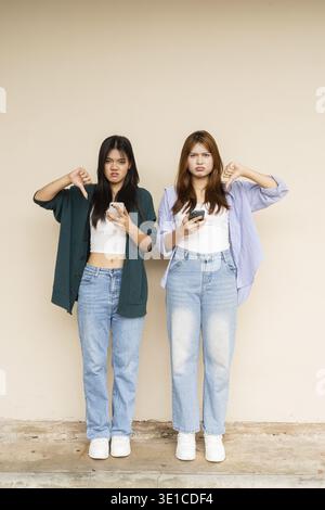 Schuss von zwei jungen asiatischen Frauen gegen eine Wand Stockfoto