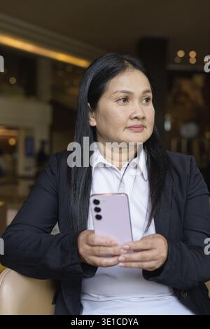 Porträt einer asiatischen Geschäftsfrau, die im Café-Restaurant mit Smartphone sitzt Stockfoto