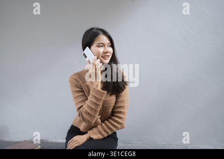 Junge asiatische Frau, die ihr Smartphone für Geschäftskommunikation im Freien in Urban City nutzt Stockfoto