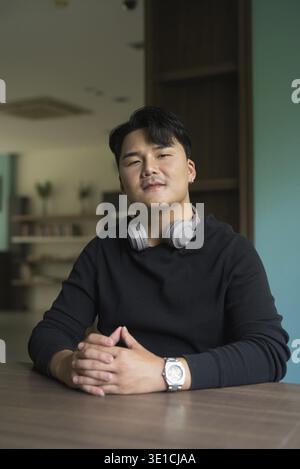 Porträt eines gutaussehenden jungen asiatischen Mannes, der drinnen sitzt Stockfoto