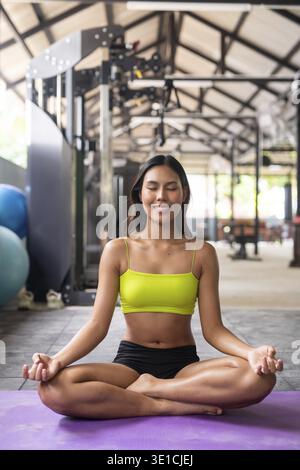 Junge, schöne asiatische Frau im Fitnessstudio, die Yoga macht Stockfoto