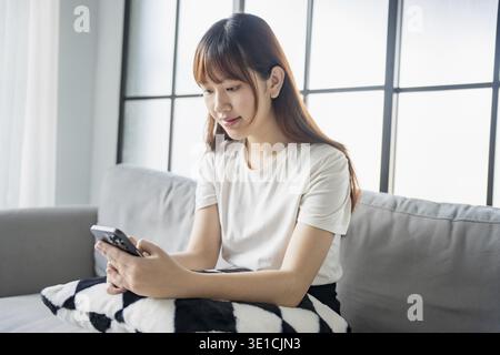 Asiatische Frau, die per Smartphone SMS Nachrichten-Browsing-Informationen verwendet Stockfoto