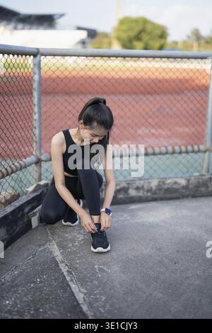 Aktive gesunde asiatische Frau binden Laufschuhe, Jogging Läufer Gesundheit und Wohlbefinden Konzept Stockfoto