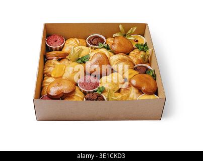 Eine verlockende Auswahl an frisch gebackenem Gebäck und Desserts in einer braunen Box. Die Auswahl umfasst Croissants, Kekse und süße Leckereien, die im Attra angeordnet sind Stockfoto