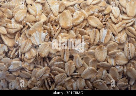 Nahaufnahme der Textur von Haferflocken, die einen natürlichen Lebensmittelhintergrund bilden. Haferflocken häufig für gesundes Frühstück und Ernährung verwendet Stockfoto