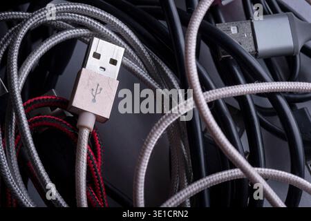 Nahaufnahme von Kabelsalat, die den modernen digitalen Lebensstil, die ständige Konnektivität und die technologische Abhängigkeit symbolisieren. Stockfoto