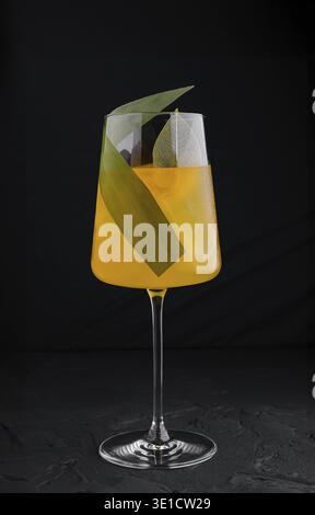 Erfrischende orangefarbene Cocktailstände auf dunklem Hintergrund, garniert mit leuchtend grünen Blättern Stockfoto