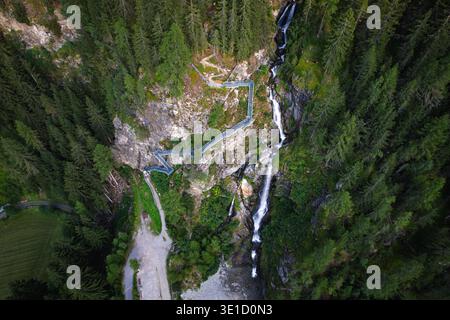 Ein Hochwinkelblick aus der Vogelperspektive mit einem kaskadierenden Wasserfall und einem malerischen Wanderweg innerhalb der majestätischen Verpeilschlucht im Kaunertal Stockfoto