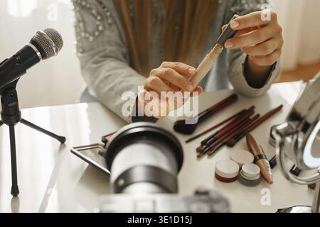 Nahaufnahme weiblicher Hände mit einem flüssigen Concealer. Frau Beauty Bloggerin, die eine Videorezension über Kosmetikprodukte macht Stockfoto