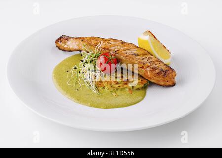 Köstlich gegrilltes Lachsfilet, serviert mit einer lebendigen grünen Sauce, Zitrone und frischer Beilage Stockfoto