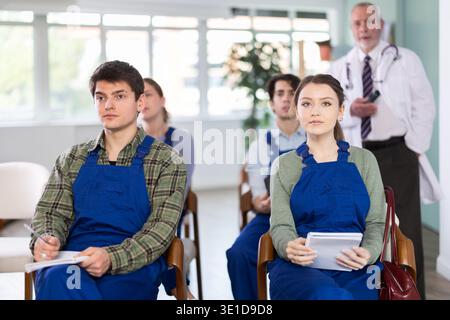 Junge Studenten in blauen Overalls, die einen Vortrag über Medizin hören Stockfoto